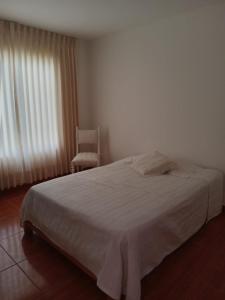a bedroom with a white bed and a chair at Habitación cerca a los Pantanos de Villa in Lima