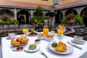 einen Tisch mit Teller mit Lebensmitteln und Gläsern Orangensaft in der Unterkunft Hotel Jose Antonio Cusco in Cusco