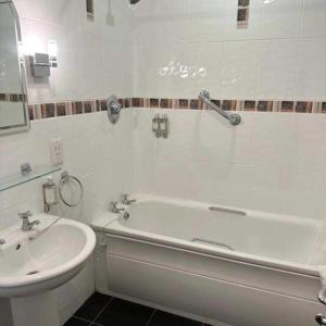 Baño blanco con bañera y lavamanos en Spacious 2 bedroom apartment in Killarney, en Killarney