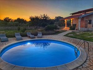 una gran piscina azul con sillas y una casa en Villa Stone Pearl with heated swimming pool, en Sveti Filip i Jakov