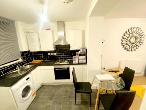 a kitchen with a sink and a table with chairs at Stylish 2 Bedroom Apartment Sleeps 5 - 3 mins walk to Mile End Station in London
