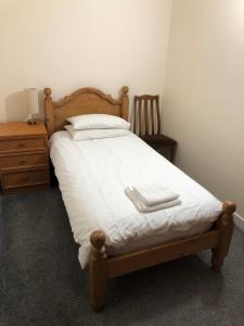 Una cama con sábanas blancas y dos toallas. en Cosy flat, Scalloway en Scalloway