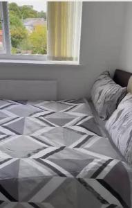 łóżko z czarno-białą kołdrą i oknem w obiekcie BLESSED HOME w mieście Bolton