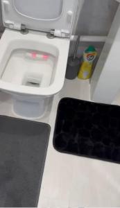 ein Badezimmer mit einem weißen WC und einem schwarzen Teppich in der Unterkunft BLESSED HOME in Bolton