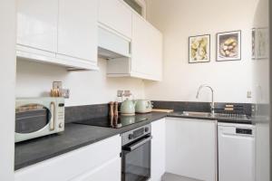 a kitchen with white cabinets and a microwave at Clarence Square Penthouse 