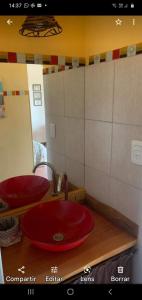 Baño con 2 lavabos rojos y espejo en Cabañas Monika - Alta en Huerta Grande