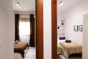 マラガにあるApartamento Agua Gibralfaro Centro con Piscinaのベッド2台と鏡付きのベッドルーム1室