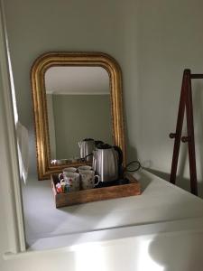 a mirror sitting on a table with a tray with tea pots at La Maison Haute in La Fosse-de-Tigné