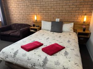 a bedroom with a bed with two red pillows on it at Three Ways Motel in Gilgandra