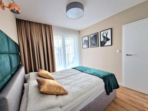 a bedroom with a bed with pillows and a window at Zakopiańskie Igliwie Apartament & Spa in Zakopane