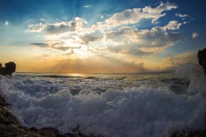 a sunset over the ocean with crashing waves at Sunset Bay Apartments in Utjeha
