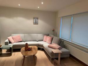 uma sala de estar com um sofá cinzento e almofadas cor-de-rosa em Apartment Testerep in Westende-Bad 150 m van het strand met garage voor 5 personen em Middelkerke