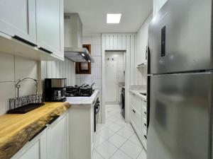 a kitchen with white cabinets and a stainless steel refrigerator at Stuttgart 210 - Apê em Gramado em local tranquilo in Gramado