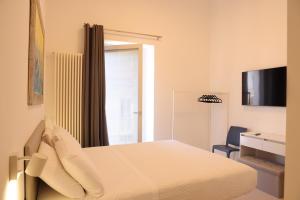 um quarto branco com uma cama e uma televisão em Ruffini Rooms em Termoli