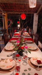 une grande table avec des assiettes et des fleurs dans l'établissement Olho D'Água Pousada, à Guaramiranga