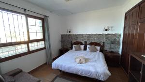1 dormitorio con cama y pared de piedra en Casa con jardín y jacuzzi, en Realejo Alto