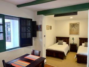 a bedroom with two beds and a table and a window at Casa Aranjuez in Bogotá