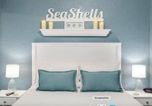 a white bed with two pillows and a sign above it at Seashells Getaway - Boat Slip, Ramp, Pool in Marathon