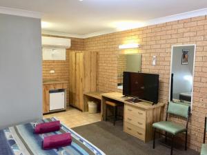 a room with a desk and a television in a room at Three Ways Motel in Gilgandra
