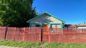 a small house behind a fence with a orange fence sidx sidx at Cabaña tío Poly in Chile Chico
