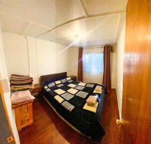 a bedroom with a bed with a checkered blanket at Cabaña tío Poly in Chile Chico