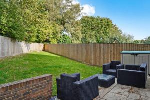 a backyard with two chairs and a table and a fence at Luxury Detached New 5 Bedroom House Ascot - Parking Private Garden in Winkfield