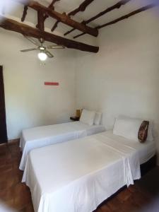 2 camas en una habitación con paredes blancas y techo en Casona CHARA, en Barichara