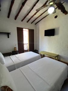 a bedroom with two beds and a flat screen tv at Casona CHARA in Barichara