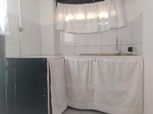 萊瓦鎮的住宿－ABI HAPPY，厨房配有带白色窗帘的桌子和窗户。