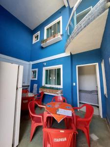 Nacif&Alcantara Suítes في Tamoios: غرفة طعام مع كراسي حمراء وجدار أزرق