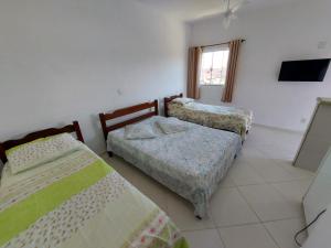 a room with three beds and a television in it at Nacif&Alcantara Suítes in Tamoios