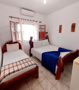 a bedroom with two beds and a window at Pousada JK in Pirenópolis