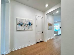 um corredor com paredes brancas e uma porta com uma pintura em Refined Luxury Living in the Heart of Irvine! em Irvine