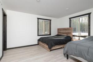 ein Schlafzimmer mit einem Bett und zwei Fenstern in der Unterkunft The Sundance Cabin in Valemount