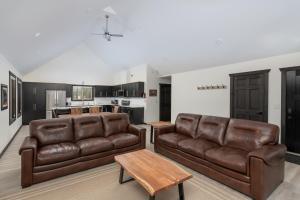 sala de estar con 2 sofás de cuero marrón y cocina en The Sundance Cabin, en Valemount