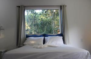 a bed in a room with a large window at Casa Mãe da Lua in Arraial d'Ajuda