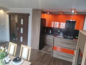 cocina con armarios naranjas, mesa y sillas en Apartament u Sylvie en Siedlce
