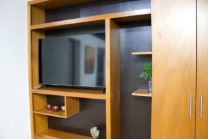 a tv in a wooden book shelf with a television at NIce & cozy apt in San José Ins. in Mexico City