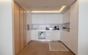 uma cozinha com armários brancos e uma porta de madeira em FLH Santos Family Spacious Flat em Lisboa
