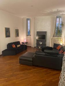 ein Wohnzimmer mit schwarzen Sofas und einem Flachbild-TV in der Unterkunft Appartamento Crisopoli in pieno centro a Parma in Parma