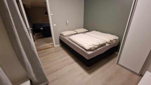 a small bedroom with a bed with white sheets at A Modern Home in Nature's Embrace in Tromsø