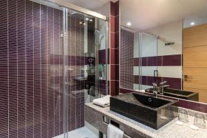 a bathroom with a sink and a glass shower at Best Western Hotel & SPA Pau Lescar Aeroport in Lescar
