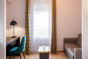 a living room with a couch and a table at Best Western Hotel & SPA Pau Lescar Aeroport in Lescar