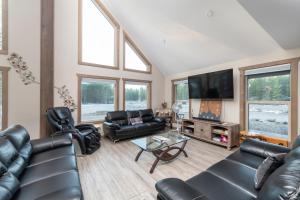 a living room with black leather furniture and a flat screen tv at Sunny Peaks in Valemount