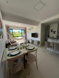 a dining room and living room with a table and chairs at Flat Cantinho do Paraíso in Guarajuba