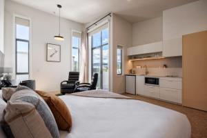 a bedroom with a large bed and a kitchen at Village Apartments at NZCIS in Upper Hutt