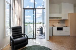 a living room with a chair and a kitchen at Village Apartments at NZCIS in Upper Hutt