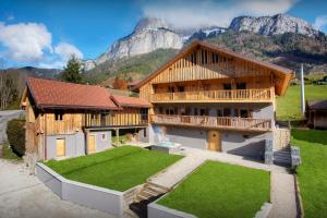 a large house with a mountain in the background at Chalet 1703 - OVO Network in Le Petit-Bornand-lès-Glières