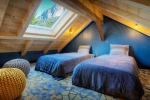 a attic room with two beds and a window at Chalet 1703 - OVO Network in Le Petit-Bornand-lès-Glières