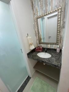 a bathroom with a sink and a mirror at Flat Cantinho do Paraíso in Guarajuba
